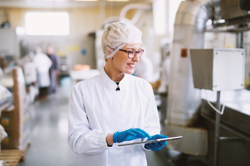 Smiley,female,worker,in,sterile,clothes,using,tablet,and,checking