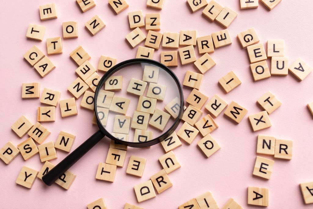 Square,letter,tiles,with,magnifying,glass,against,pink,background.,search